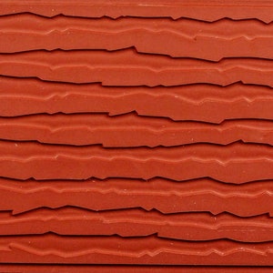May include: A close-up of a red rubber stamp with a textured surface that resembles a series of horizontal lines.