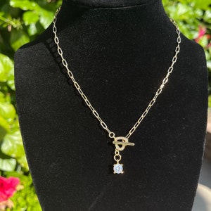 May include: A gold chain necklace with a toggle clasp and a single clear rhinestone pendant.