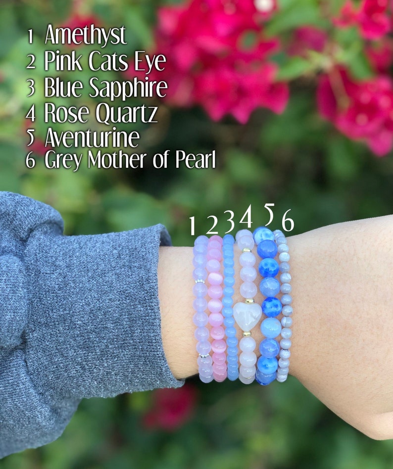Puede incluir: Seis pulseras apiladas con cuentas de diferentes colores. Las pulseras est&aacute;n etiquetadas del 1 al 6. Las etiquetas corresponden a las siguientes piedras: Amatista, Ojo de Gato Rosa, Zafiro Azul, Cuarzo Rosa, Aventurina y Madreperla Gris.