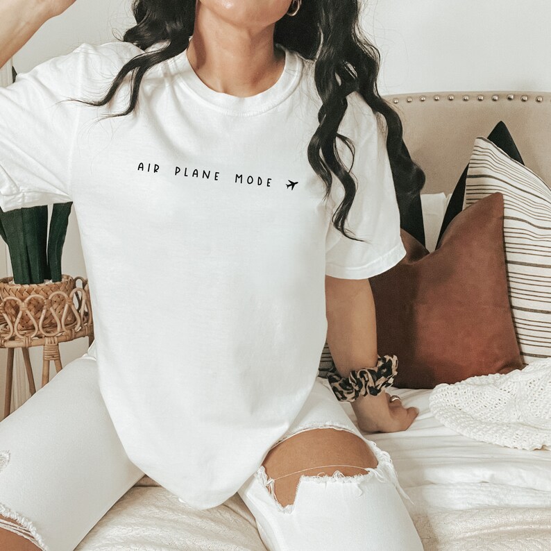 Peut inclure: T-shirt blanc avec le texte "AIR PLANE MODE" et une petite ic&ocirc;ne d'avion imprim&eacute; sur le devant.