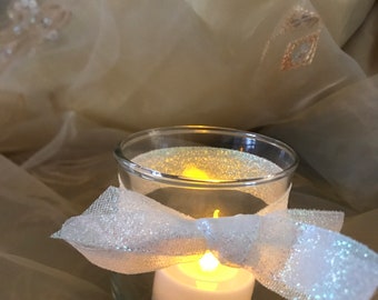 Clear glass container with white LED lighted candle and tied ribbon