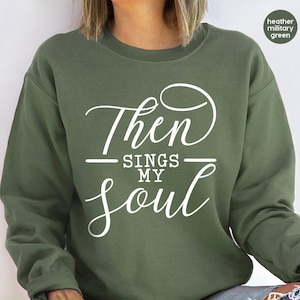 May include: A green sweatshirt with the text "Then Sings My Soul" in white lettering.