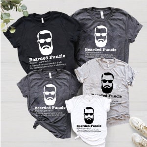 May include: Set of four t-shirts in black, grey, and white featuring a bearded man with sunglasses and the text "Bearded Funcle" with a definition. The definition reads: " /bi(a)rdid fugnh-kuh 1/ 1. The most superior breed of uncle. The coolest and most fun uncle known."
