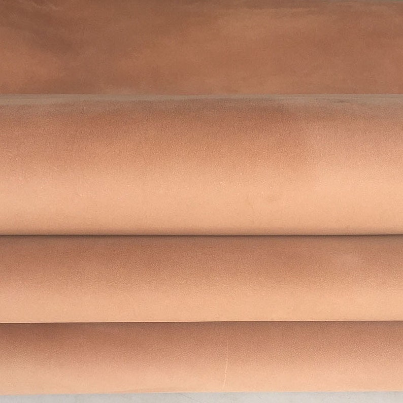 May include: Close-up of a folded piece of light brown leather. The leather has a smooth, velvety texture.