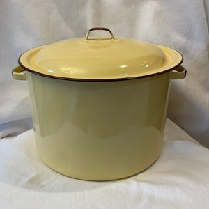 May include: A yellow enamelware pot with a lid and two handles. The pot has a brown rim around the top.