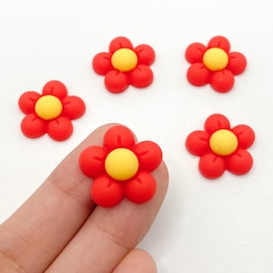 Puede incluir: Cinco botones rojos en forma de flor con centros amarillos. Los botones son pequeños y tienen una apariencia 3D.