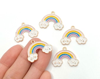 May include: Five gold-tone rainbow charms with white clouds. Each charm has a pink, yellow, blue, and purple rainbow with a gold outline. The clouds have a white enamel finish with black dots for eyes.