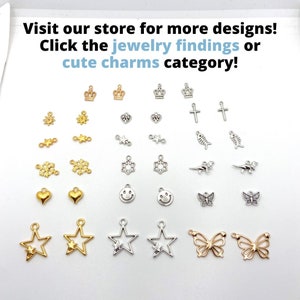 May include: A collection of small jewelry charms in gold and silver tones. The charms include crowns, hearts, stars, butterflies, crosses, snowflakes, and smiley faces. Text on the image reads: Visit our store for more designs!