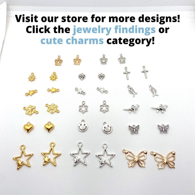 May include: A collection of small jewelry charms in gold and silver tones. The charms include crowns, hearts, stars, butterflies, crosses, snowflakes, and smiley faces. Text on the image reads: Visit our store for more designs!
