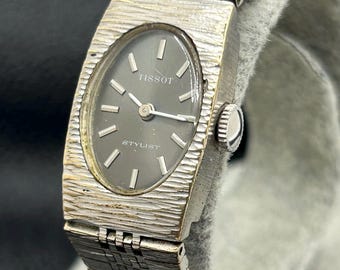 Reloj mecánico de cuerda vintage Tissot Stylist para mujer con caja ovalada y brazalete en tono plateado texturizado.