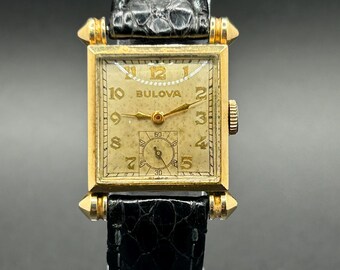 Reloj unisex vintage Bulova "Knickerbocker" Art Déco de los años 40 con caja cuadrada dorada, segundero pequeño y esfera patinada. Cuerda manual.