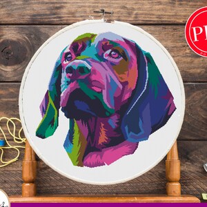 May include: A colorful cross stitch pattern of a dog's head. The dog is a brown and black breed with a long snout and floppy ears. The pattern is 269 x 269 stitches and uses 21 colors from the DMC palette.