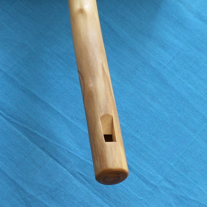 May include: A wooden flute with a single finger hole. The flute is brown and has a natural wood finish.