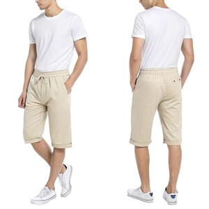 May include: A pair of beige linen shorts with a drawstring waist and cuffed hems. The shorts are shown on a model wearing a white t-shirt.
