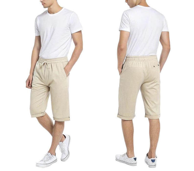 May include: A pair of beige linen shorts with a drawstring waist and cuffed hems. The shorts are shown on a model wearing a white t-shirt.