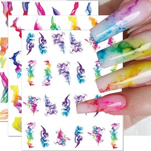 May include: Three sheets of colourful nail art stickers with a rainbow swirl design. The stickers are shown on a model's nails.