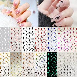 May include: Nail art stickers with star designs in a variety of colours, including white, red, black, blue, and gold. The image also shows examples of the stickers applied to nails, demonstrating the different designs.