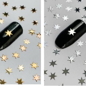 May include: Two images showing nail art with gold and silver star shaped nail glitter. The glitter is scattered around the nail and on a white surface.