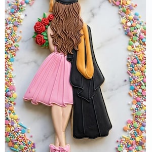 May include: A graduation-themed cookie decorated with a mortarboard, gown, and a pink dress. The cookie features a graduate holding a bouquet of red roses. The background is decorated with colorful sprinkles.