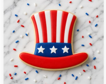 Può includere: Un biscotto patriottico a forma di cappello rosso, bianco e blu dello Zio Sam, decorato con stelle bianche su una fascia blu. Granelli rossi, bianchi e blu circondano il biscotto su una superficie di marmo. Una festa per il giorno dell'Indipendenza.