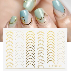 May include: Gold nail stickers with a white background. The stickers feature a variety of designs, including arches, swirls, and the text "Live being you, love is now, believe you can, you're limitless, take the choice". The stickers are labeled "STZ-GS104".