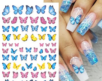 May include: Sheet of nail art stickers featuring various butterfly designs in blue, pink, and yellow. The stickers include butterflies of different sizes and styles. The image also shows a hand with a manicure featuring butterfly nail art.