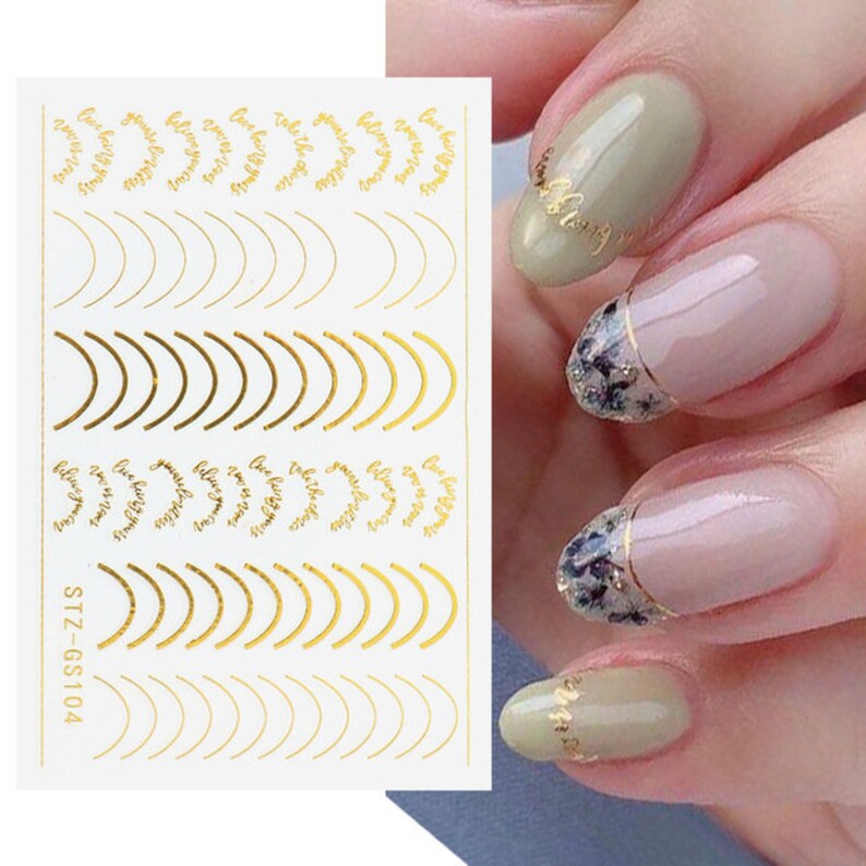 May include: Gold nail art stickers with a variety of designs, including curved lines, half circles, and the phrase "Love yourself" repeated multiple times. The sticker sheet is labeled "STZ-GS104".