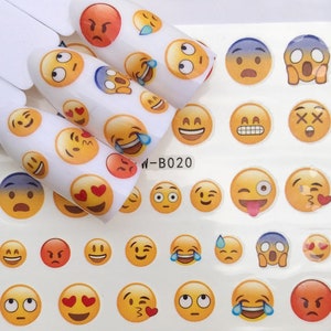 Op de afbeelding: Een vel met gele en witte nagelstickers met verschillende emoji-gezichten. Het vel bevat een verscheidenheid aan uitdrukkingen, waaronder blij, verdrietig, verrast en boos. De tekst "W-B020" staat op het vel gedrukt.