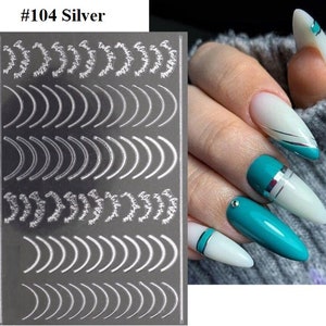 May include: Silver nail art stickers with a variety of curved and floral designs. The sticker sheet is labeled #104 Silver.