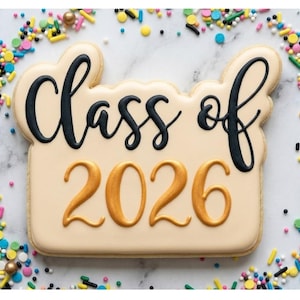 Może przedstawiać: Ozdobione ciastko z napisem "Class of 2026" w czarnym i złotym lukrze. Ciastko otoczone jest kolorową posypką na białej marmurowej powierzchni. Uroczysta uczta na ukończenie szkoły.