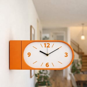 May include: An orange wall clock with a white face and black hands. The clock has an oval shape with the numbers 3, 6, 9, and 12 in orange. The clock is mounted on a white wall.