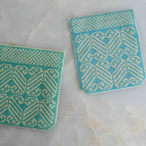 Peut inclure: Deux sous-verres tissés turquoise et blanc avec un motif géométrique. Les sous-verres sont faits d'un matériau doux et texturé.