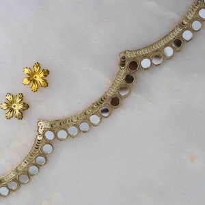 May include: Gold trim with round, mirrored sequins. Two gold flower-shaped embellishments are on the left side of the image.