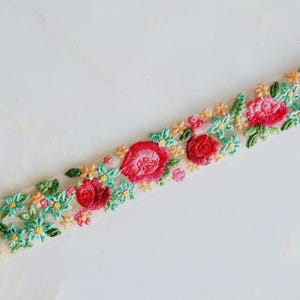 Può includere: Bordura floreale ricamata con rose rosse, fiori rosa e gialli e foglie verdi. La bordura è su uno sfondo color crema. Questa bordura decorativa è ideale per cucito e progetti artigianali.