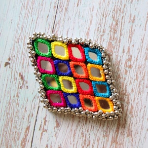 Op de afbeelding: Een ruitvormige patch met een raster van kleine spiegeltjes, omlijst door levendig, meerkleurig borduurgaren in groen, geel, rood, blauw en roze, afgewerkt met een rand van kleine, metallic zilverkleurige kraaltjes langs de zijkanten.