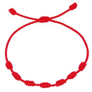 May include: A red string bracelet with knotted accents. The bracelet is tied with a slip knot.