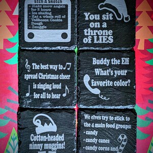 May include: Six black slate coasters with white text and images. The coasters feature Christmas-themed sayings and illustrations, such as "You sit on a throne of lies" and "Buddy the Elf, what's your favorite color?"