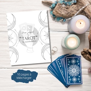 May include: A white journal with the text "Mon journal de TAROT & manifestation" and a deck of blue tarot cards. The journal has a crescent moon and star design. Two lit candles and a beaded necklace are also visible.
