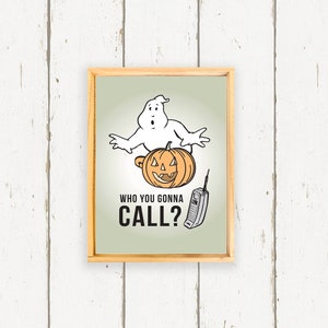May include: A framed print with a cartoon ghost holding a jack-o'-lantern. The text below reads "Who you gonna call?" with a retro cell phone next to it.