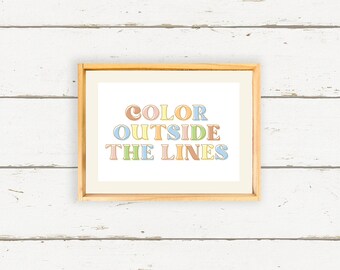 May include: A framed print with the text "COLOR OUTSIDE THE LINES" in a colorful, retro font. The letters are outlined in black and filled with pastel colors.