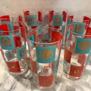 May include: Set of eight vintage drinking glasses with a turquoise and red checkered pattern and gold accents. Each glass features a different crest design.