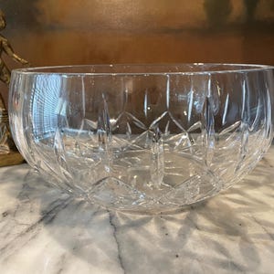May include: A large, clear crystal bowl with a cut-glass design. The bowl is round and has a wide opening.