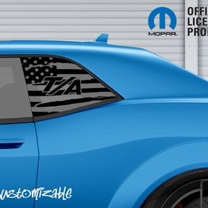 May include: A light blue car with a black and white American flag design on the rear window. The text "T/A" is visible on the flag. The image also includes the Mopar logo and the words "OFFICIAL LICENSED PRODUCT".