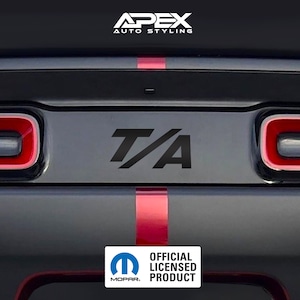Può includere: Emblema nero "T/A" sul pannello posteriore di un'auto, con strisce rosse e nere. L'immagine include il logo "Apex Auto Styling" e il logo Mopar "Official Licensed Product".