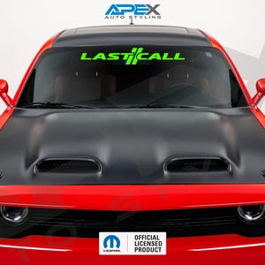 Puede incluir: Un coche rojo con capó negro y una pancarta verde "LAST CALL" en el parabrisas. El coche tiene un capó negro con dos rejillas de ventilación y una pegatina "Mopar Official Licensed Product".
