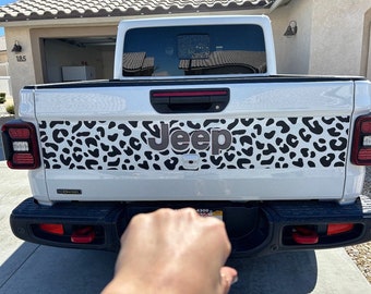 May include: White Jeep truck with a black and white leopard print design across the tailgate. The word "Jeep" is in gray lettering. The truck has red taillights and a black bumper.