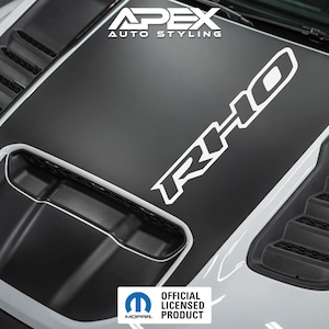 May include: A close-up of a car hood with a black center section and white accents. The hood features the text "RHO" in white, along with the "APEX AUTO STYLING" logo. An official licensed product logo is visible.
