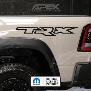May include: A tan truck bed with a black TRX decal. The truck has a black tire and a red taillight. The image also includes the Apex Auto Styling logo and an Official Licensed Product badge.