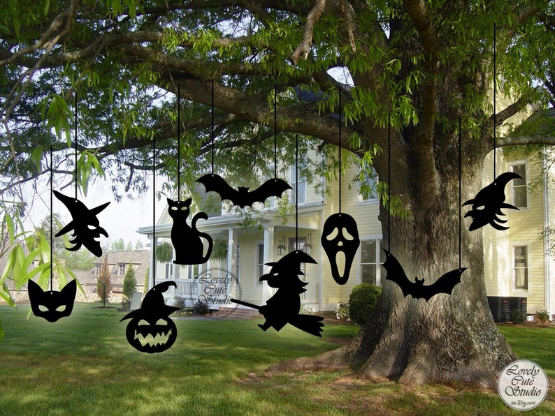 May include: Black Halloween cutouts hanging from a tree branch. The cutouts include a witch, a cat, a bat, a ghost, a pumpkin, and a mask. The cutouts are made of metal and are perfect for decorating your home for Halloween.