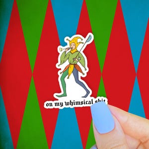 May include: A sticker featuring a cartoon jester in green, yellow, and blue attire, playing a horn and holding a staff. The text "on my whimsical shit" is below the jester. The background is a repeating pattern of red, green, and blue diamonds.